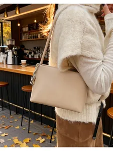 Detail of soft apricot leather shoulder bag featuring silver chain and metal charm accents