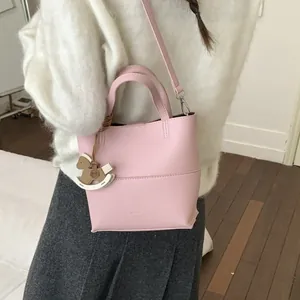 Sac seau rose en cuir souple avec pendentif cheval à bascule et bandoulière réglable
