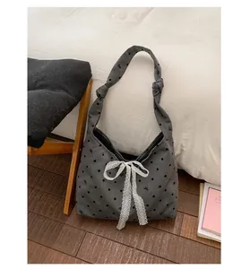 Detailed view of grey canvas tote featuring black polka dots and white lace bow decoration