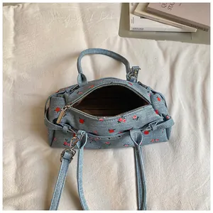 Detail of denim bag with red rose embroidery, striped lining and detachable shoulder strap