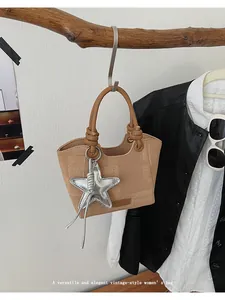Close-up of khaki checkered vintage bucket bag with silver star pendant on a wooden branch