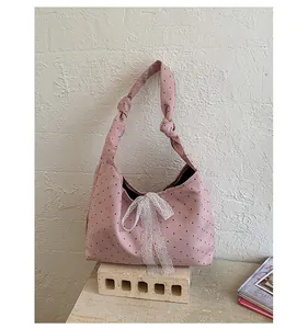 Detail of pink polka dot canvas tote bag featuring a white lace bow and knotted strap