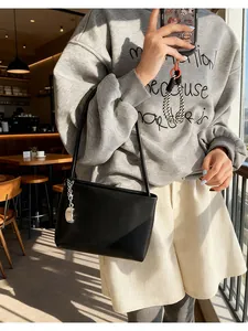 Detail of minimalist black soft leather bucket bag with silver metal pendant accent