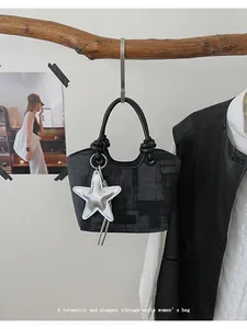 Detailed close-up of a vintage dark grey bucket bag with textured weave and star charm