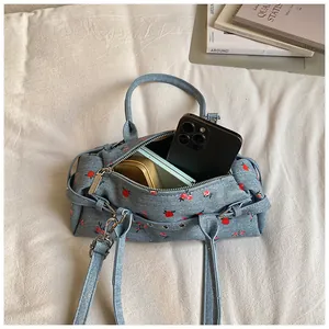 Detail showing red flower embroidery on light blue canvas bag with interior capacity