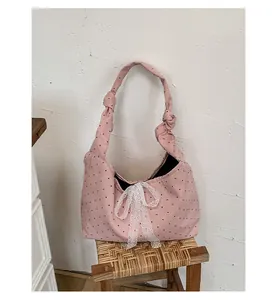 Detail of pink polka dot canvas tote featuring a white lace bow and knotted handle design