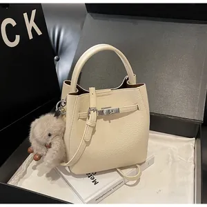 Dettaglio della borsa a secchiello in pelle grana color crema con chiusura metallica