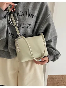 Close-up of a soft light green bucket bag with silver crescent charm and dual straps