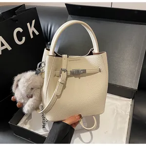 Dettaglio borsa in pelle color crema con chiusura a scatto argento e ciondolo a coniglio