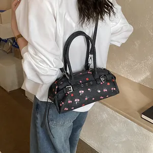Detail of navy denim tote with red cherry embroidery and adjustable silver strap buckle