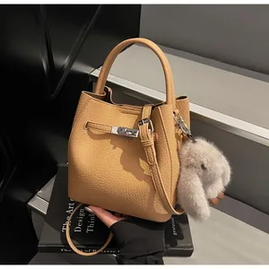 Dettaglio della borsa a secchiello color cuoio con chiusura a scatto e ciondolo a coniglio