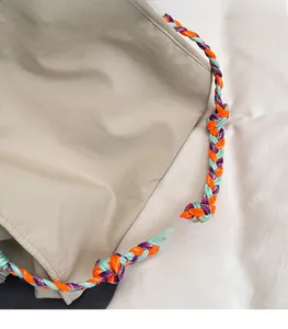 Dettaglio borsa tote beige in tessuto a quadretti con manici in corda intrecciata colorata