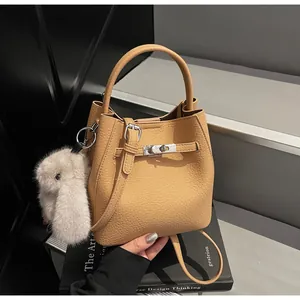Dettaglio ravvicinato di una borsa a secchiello in pelle color cammello con fibbia argento