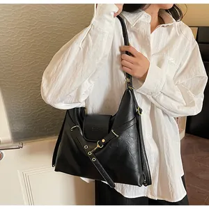 Dettaglio della borsa tote nera vintage in pelle con hardware dorato portata da modella
