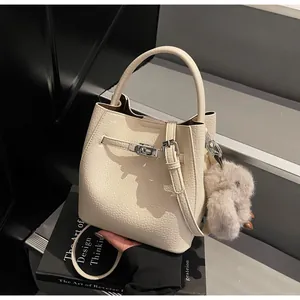 Dettaglio borsa a secchiello in pelle beige con chiusura argento e ciondolo a coniglio