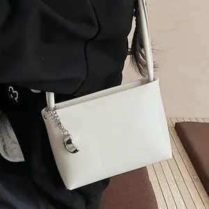 Minimalist white leather bucket bag with silver charm pendant for casual commuting
