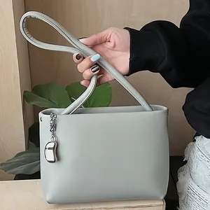 Minimalist sage green soft leather bucket bag with silver charm for daily commute