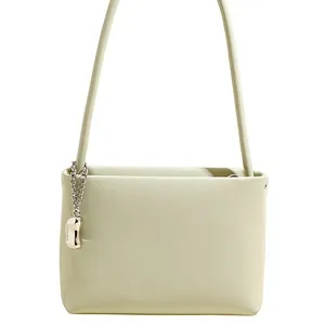 Minimalist soft leather bucket shoulder bag in pale green with a silver metallic charm