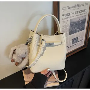 Dettaglio della borsa a secchiello in pelle crema con chiusura argento e ciondolo