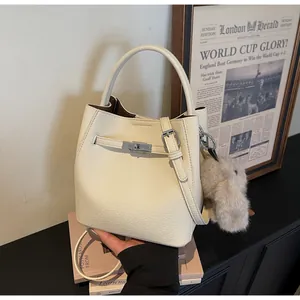 Dettaglio della borsa a secchiello in pelle crema con chiusura a scatto e charm a coniglio
