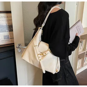 Dettaglio di una grande borsa tote in pelle crema con finiture dorate e texture a pieghe