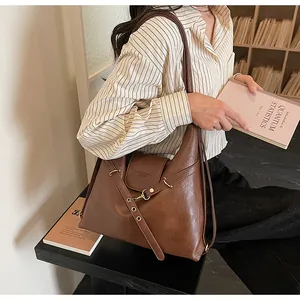 Dettaglio borsa hobo in pelle marrone con tracolla regolabile e logo in rilievo