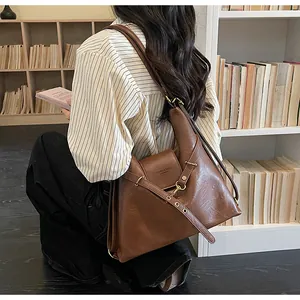 Dettaglio della borsa tote in pelle marrone scuro con fibbia in metallo e design a pieghe