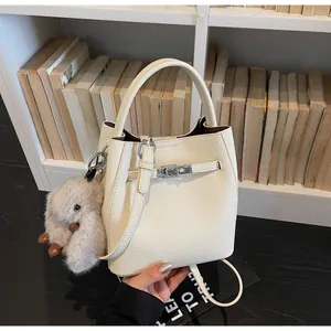 Dettaglio della borsa a secchiello in pelle crema con chiusura in metallo e charm coniglio