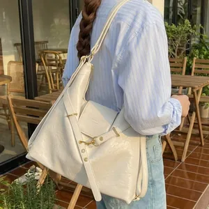 Borsa tote beige minimalista di grande capacità indossata da una modella in un caffè all'aperto