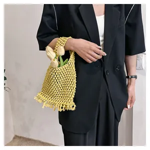 Detalle del bolso de ganchillo amarillo con flecos y tulipanes, mostrado en modelo