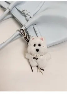 Detail eines süßen weißen Plüschhund-Anhängers mit Perlenkette an blauer Einkaufstasche