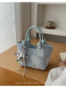 Close-up of light blue denim bucket bag featuring knotted handles and silver star charm