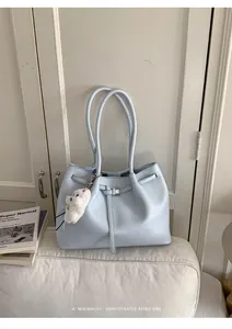 Detail der hellblauen Shopper-Tasche aus Kunstleder mit Schnalle und Plüschtier-Anhänger