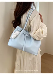 Hellblaue minimalistische Einkaufstasche mit Schnalle und Bärenanhänger am Modell
