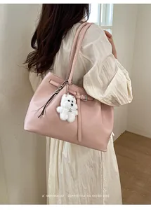 Seitenansicht der rosa Ledertasche mit gestreiftem Band und weißem Plüsch-Anhänger
