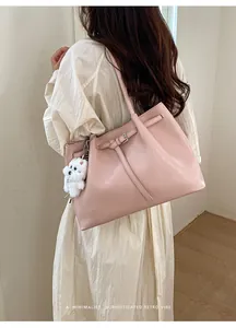 Minimalistische rosa Leder-Einkaufstasche mit Plüschwelpen-Anhänger getragen vom Model