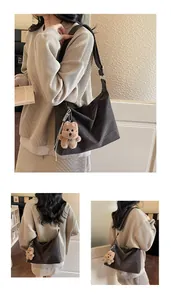 Detail of dark brown matte leather tote bag featuring a cute plush bear charm decoration