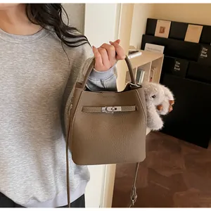 Dettaglio della borsa a secchiello in pelle marrone scuro con chiusura in metallo e charm