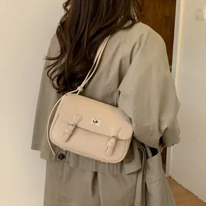 Minimalist beige pebble leather satchel bag with silver clasp shown on a model