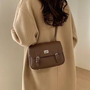 Brown textured leather crossbody Cambridge bag worn with a stylish camel wool coat