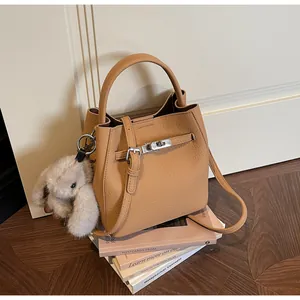 Dettaglio di una borsa a secchiello in pelle marrone con chiusura argento e ciondolo a coniglio