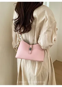 Detail of pink lychee leather handbag featuring silver twist lock and leopard plush charm