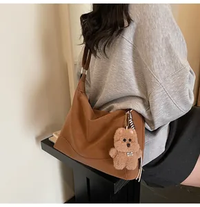 Detail of a dark brown matte leather hobo bag featuring a cute brown plush bear charm