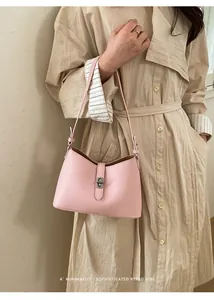 Detail of pink crossbody bag with pebbled leather texture and metal turn-lock closure