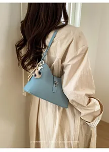 Close-up of light blue pebbled leather handbag featuring silver twist-lock and plush charm