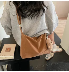Detail shot of brown frosted hobo bag with teddy bear charm and wide shoulder strap