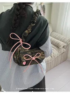 Detail of camouflage baguette bag with pink bow ribbon and ruched shoulder strap