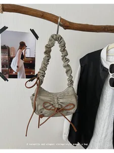 Detail of vintage canvas baguette bag with ruffled handle and brown bow decoration