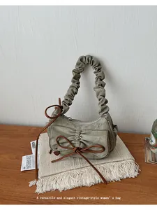Detailed shot of sage green canvas bag with pleated handle and ribbon bow accent