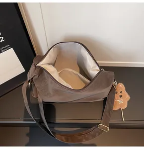 Detailed view of dark brown matte tote bag with herringbone lining and plush bear charm